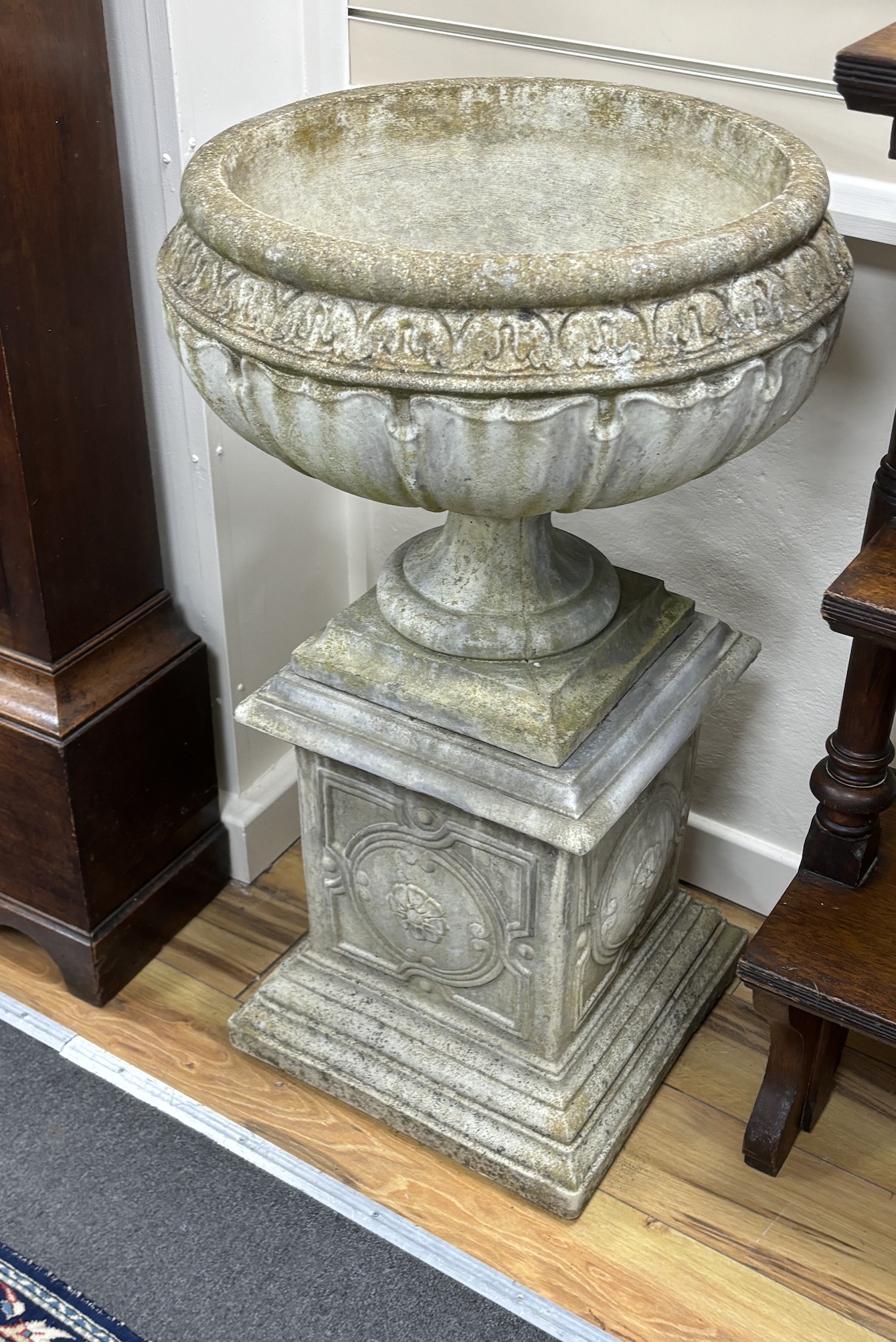 A set of three circular reconstituted stone garden urns on square plinths, diameter 54cm, height 95cm